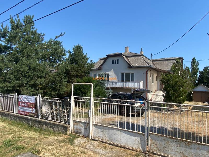 Rodinný dom na Hlavnej ulici v Borši s kovovým plotom, garážou a stromami.